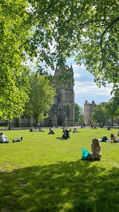 people sitting on the grass in front of an old building