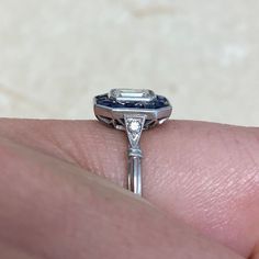 a close up of a person's hand holding a ring with a diamond on it