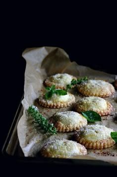 small pastries are sitting on a tray with green leafy garnishes