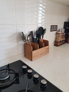 a stove top oven sitting next to a wooden holder filled with utensils and spoons