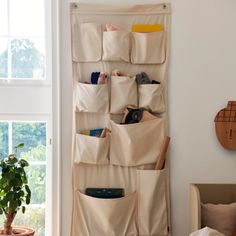 an over the door storage bag hanging on a wall next to a potted plant