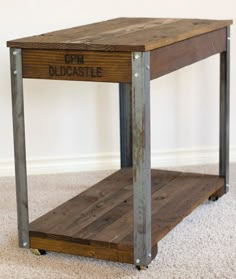 a small wooden table with metal legs and a sign on the top that says oldcastle