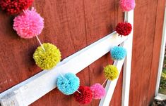 colorful pom poms hanging on the side of a wooden door