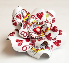 a flower made out of playing cards on a white surface with red dots and hearts