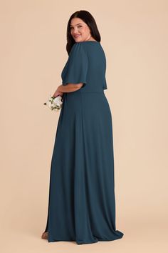 a woman in a long blue dress smiles at the camera while wearing a white bouquet