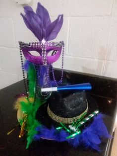 a mardi gras mask and feather hat on a counter