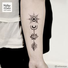 a woman's arm with tattoos on it and a cross, compass, sun and moon