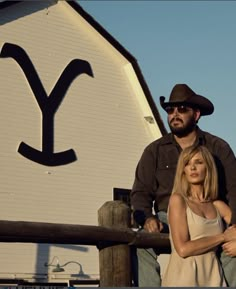 a man and woman standing next to each other in front of a building with the y on it