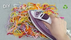 someone is ironing colored paper with an electric iron on top of the pile of plastic cords