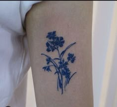 a small blue flower tattoo on the arm