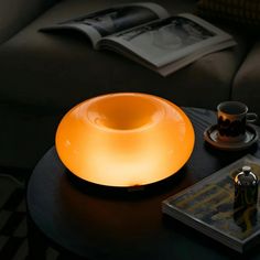 a table with a lamp on top of it next to a book and coffee cup