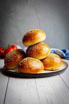 sesame bagels stacked on top of each other on a plate with tomatoes in the background