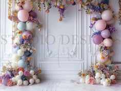 an arch made out of balloons and flowers is shown in front of a white wall