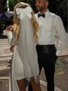 a man and woman standing next to each other on the street with an umbrella over their heads