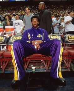 a man sitting on top of a bench in front of a crowd at a basketball game