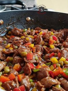 beef and peppers cooking in a wok on the stove