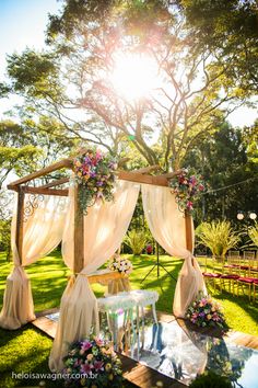 an outdoor wedding setup with sheer draping and flowers on the table, surrounded by greenery