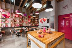 a room filled with lots of tables and chairs next to a wall covered in shelves