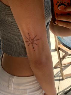 a woman's arm with a small star tattoo on the left side of her right arm