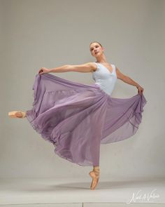 a woman in a white tank top and purple skirt is doing a ballet move with her hands