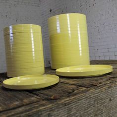 three yellow cups and plates on a wooden table