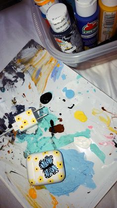 an artist's palette with paint and brushes on it next to some other art supplies