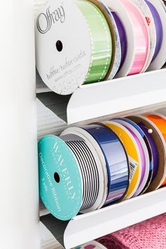 several different colored spools of thread are on the shelf next to each other