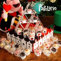 a table topped with lots of cupcakes next to a stuffed animal holding a heart