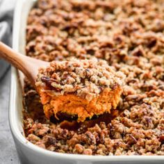 a casserole dish with a wooden spoon scooping out some food from it