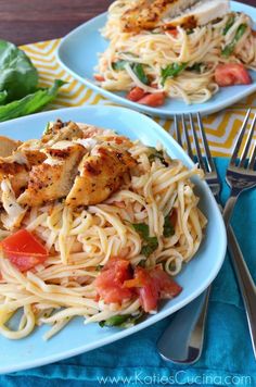 two plates of pasta with chicken, tomatoes and spinach