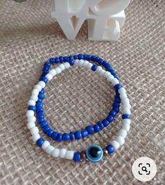 two blue and white bracelets sitting on top of a table next to a plastic object