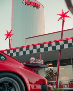 a red sports car parked in front of a building with three stars on it's roof