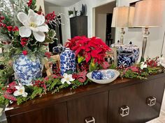 a christmas display with blue and white vases, poinsettias and greenery