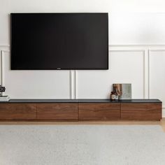 a flat screen tv mounted to the side of a wooden entertainment center in a living room