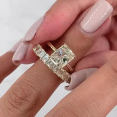 a woman's hand holding an engagement ring with two diamonds on top of it