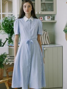 This product is an elegant puff stripe shirt dress that combines comfort with chic styling. The dress features a classic collar and a full-length button placket, along with a flattering waist tie that enhances its silhouette. It's designed with a mid-length hem and crafted from a lightweight fabric, making it perfect for both day wear and casual evening events. - The shirt dress's tailored collar and button-down front give it a polished look with a nod to classic shirt styling.- Puff sleeves add a contemporary edge and a touch of femininity to the overall design.- A detachable tie at the waist allows for a customizable fit and adds definition to the wearer's figure.- Its stripe pattern and breezy fabric make it a go-to choice for staying stylish during warmer weather. Shirt Dress Vintage, Preppy Shirt, Casual Evening, Blue Shirt Dress, Striped Shirt Dress, Overall Dress, Blue Shirt, Classic Shirt, Collar Dress