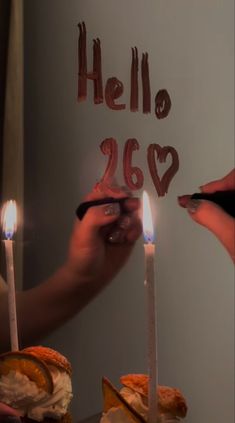 two people holding candles in front of a cake with the word hello 26 written on it