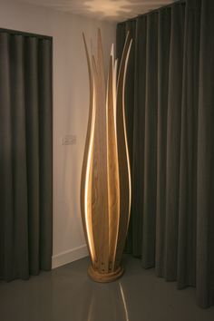 a tall wooden vase sitting in front of curtains