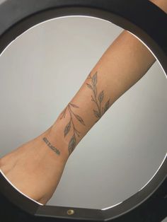 a woman's leg with a tattoo on it in front of a round mirror