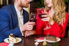 two people sitting at a table holding wine glasses