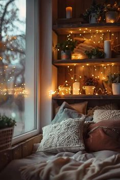 a bed with pillows and some lights in the window sill next to a potted plant