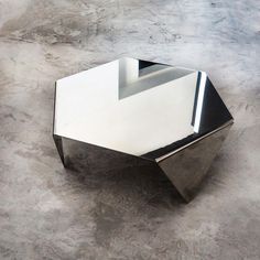 a modern coffee table with mirrored top on concrete floor