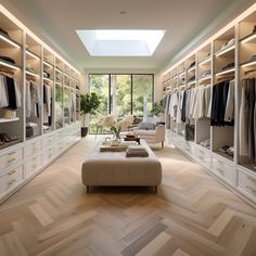 a large walk in closet with lots of clothes on shelves and drawers, along with a footstool