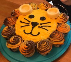 a lion cake on a plate with cupcakes