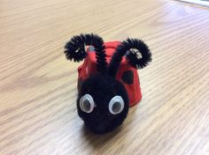 a black and red stuffed animal with eyes on it's head sitting on a wooden table