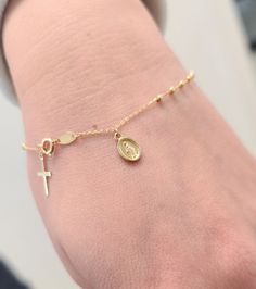 Elevate your faith-inspired style with our Rosary Bracelet featuring a Dangling Miraculous and Cross. Crafted with precision in solid 14K yellow gold, this bracelet exudes elegance and devotion. The delicate beads, each measuring 1.5mm, symbolize prayers and devotion, while the Miraculous medal (8x6mm) and cross (10x6mm) add a touch of sacred beauty. With a comfortable 7-inch length, this bracelet is a timeless expression of faith and grace, perfect for daily wear or special occasions. Details: Spiritual Yellow Gold Charm Bracelet, Dainty Yellow Gold Bracelets With Charms, Spiritual Yellow Gold Beaded Jubilee Bracelets, Spiritual Yellow Gold Beaded Jubilee Bracelet, Adjustable Yellow Gold 14k Rosary Bracelet, Adjustable 14k Yellow Gold Rosary Bracelet, Spiritual Yellow Gold Bracelet, Yellow Gold Plated Spiritual Bracelet, Adjustable Gold Sterling Silver Rosary Bracelet