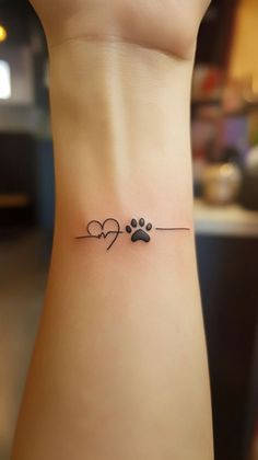 a small dog paw and heart tattoo on the side of a woman's ankle