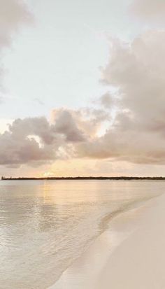 the sun is setting on an empty beach