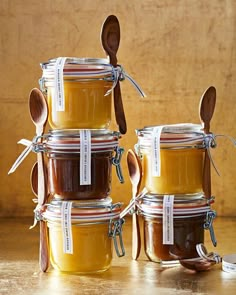 four jars with spoons are stacked on top of each other and one is filled with honey