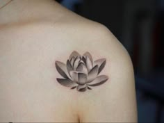 a black and white photo of a woman's shoulder with a lotus tattoo on it